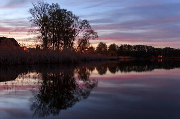 Foto bomen die zich weerspiegelen in het meer tegen de hemel in de schemering