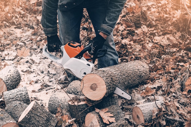 Bomen kappen in de herfst in het bos Man's handen houden een kettingzaag vast