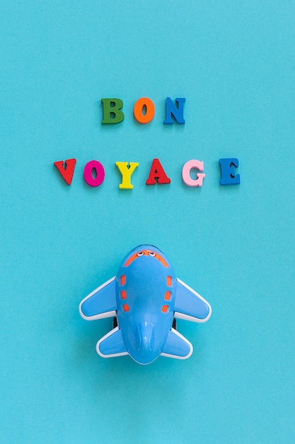 Bon voyage and children's funny toy plane on blue background. concept travel, tourism