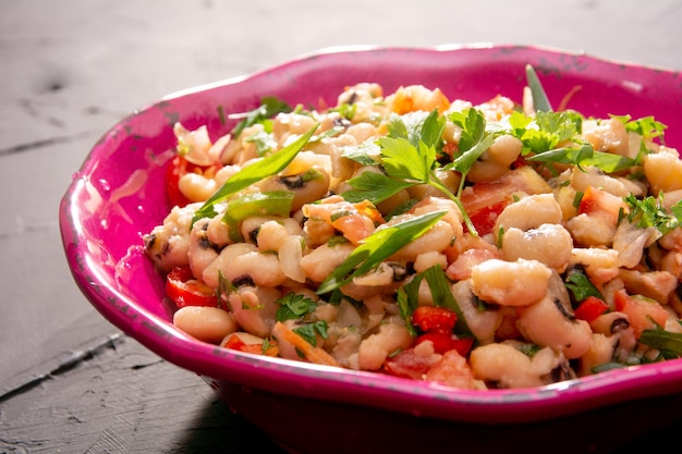 Bonensalade een zelfgemaakte salade met bonen, tomaten, uien, paprika's en kruidenclose-up op een bord