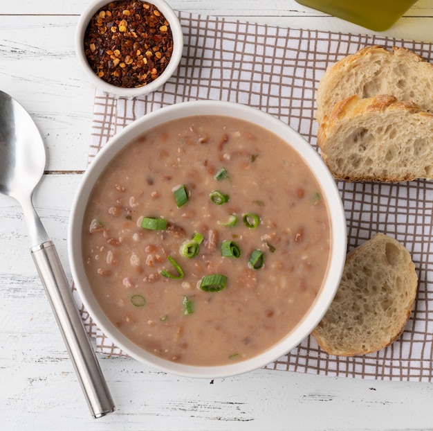 Bonensoep in een kom met sneetjes brood en kruiden op houten tafel