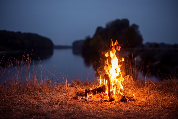 Bonfire on the bank of the river in the evening. Atmospheric photo of a campfire near the river