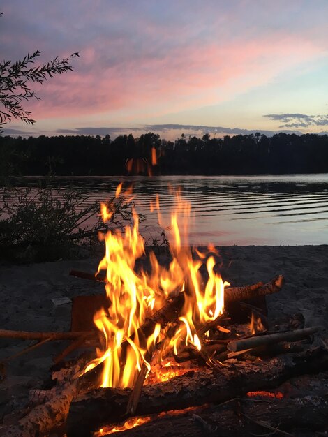 Photo bonfire by lake during sunset