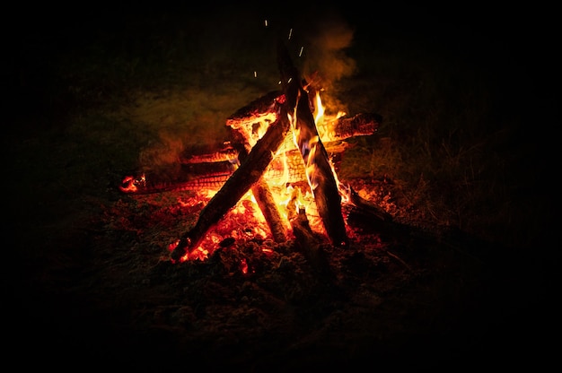 焚き火。黒で隔離の夜のキャンプファイヤー。燃える丸太と薪。夜の焚き火。暗闇の中でキャンプファイヤーで燃えている丸太