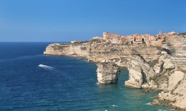 Bonifacio citadel  above  limestone cliff overlooking the sea on clear blue sky- corsica