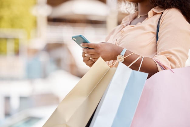 Boodschappentasverkoop en smartphone met zwarte vrouw luxe boetiek voor klant en online aankoop in de stad Afro-Amerikaanse vrouwelijke telefoon en kleding van retailtherapie voor stadsmarktreis