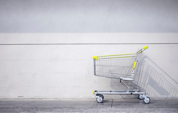 Boodschappenwagentje geparkeerde grijze bakstenen muur buiten een supermarkt