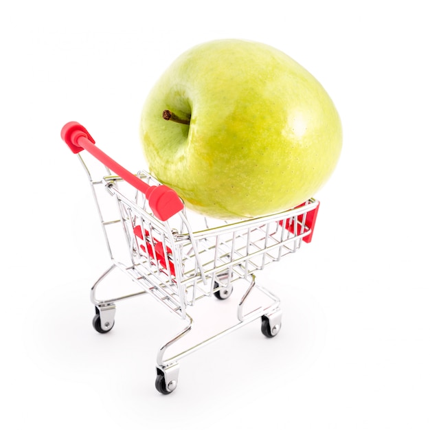 Boodschappenwagentje met grote groene appel op wit. Fruit kopen bij de supermarkt. Zelfbedieningssupermarkt vol winkelwagentje. Verkoop, overvloed, oogstthema