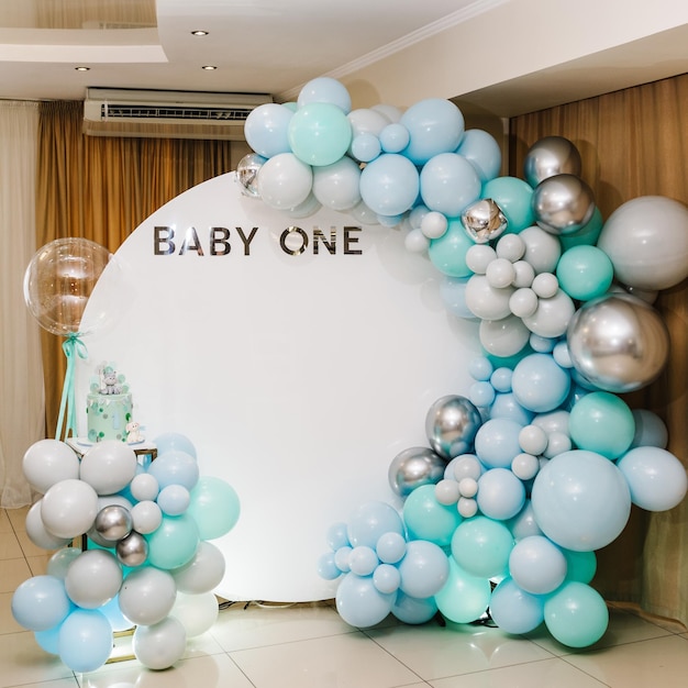 Boog gedecoreerd met blauw groen grijze en zilveren ballonnen Baby one party Trendy Taart voor 1 jaar Verjaardag Taart op een achtergrond fotowand Heerlijke ontvangst op een verjaardagsfeestje