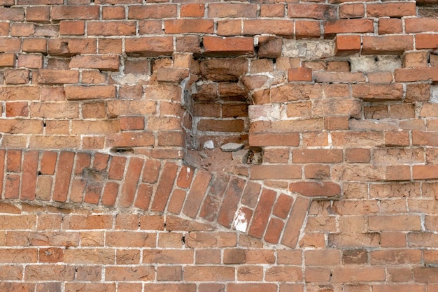 Boog in oud metselwerk op de verlaten close-up van het oude huis rode bakstenen muurfragment