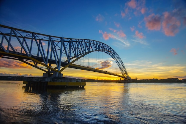 Boogbrug over de rivier tegen de hemel bij zonsondergang