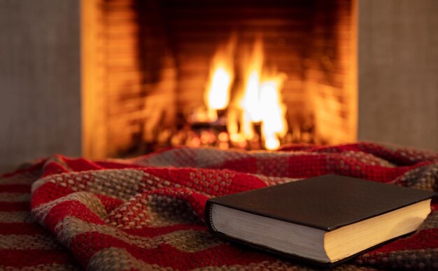 Book on a blanket fireplace burning firewood background Reading and relax near the fire