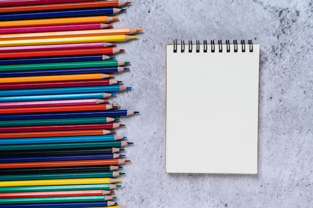 A book and color pencils top view with clear notepad