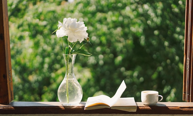 Book cup coffee and white peonies on a wooden window Romantic concept Vintage style