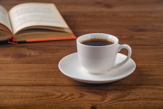 Book and cup of coffee on wooden surface