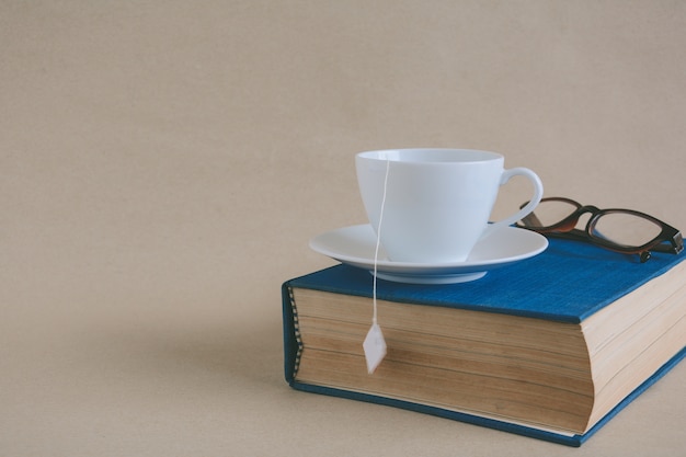 Book glasses and tea on the desk with study and education concept