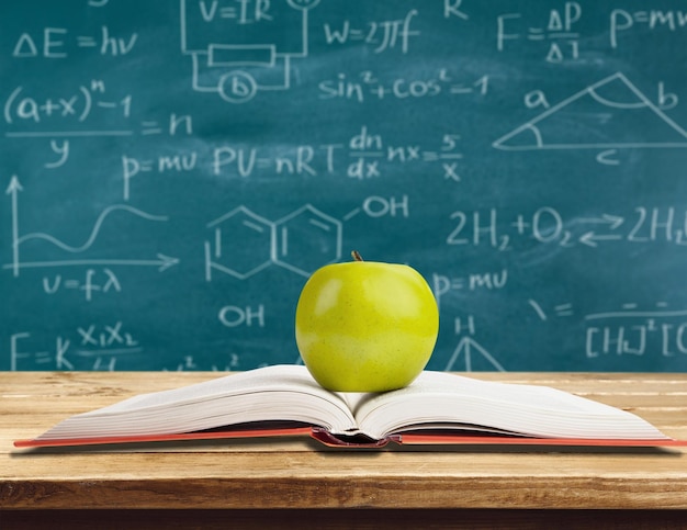 book and green apple isolated on background