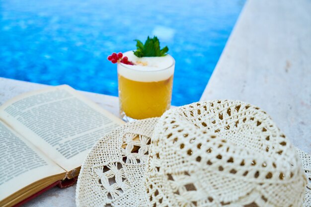 Book, hat and alcoholic fruit cocktail