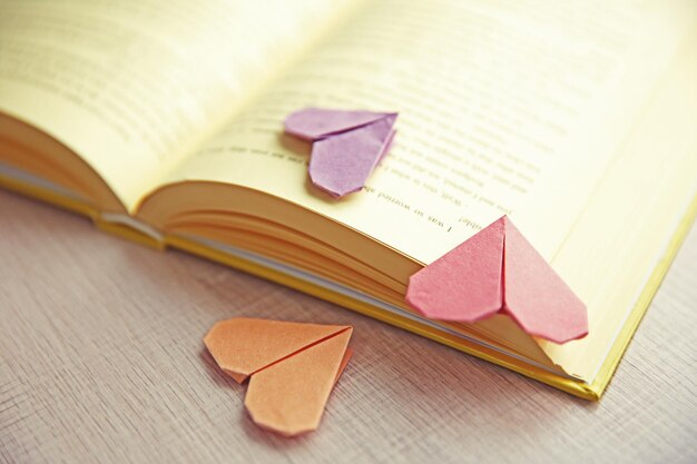 Book and heart shaped bookmark on a light wooden background