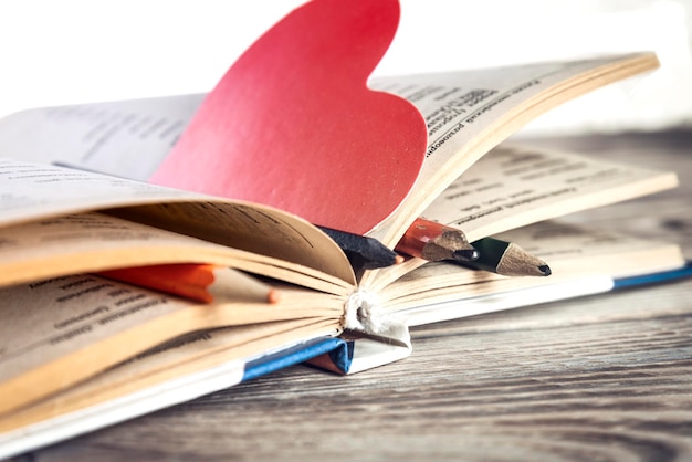 Book and heart shaped bookmark on wooden table