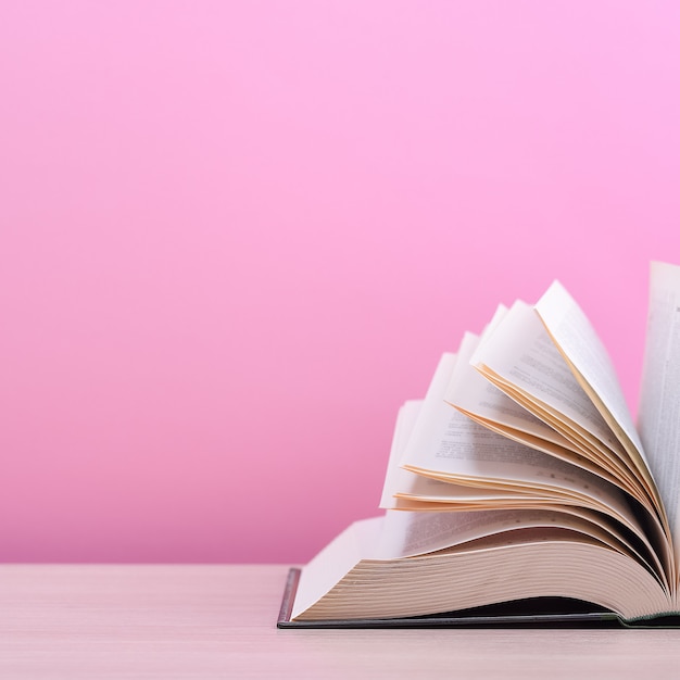 The book is open, lying on the table, sheets fanned out on a pink background.