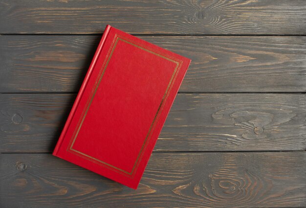 The book is in a red cover on a gray wooden background with a place for the text