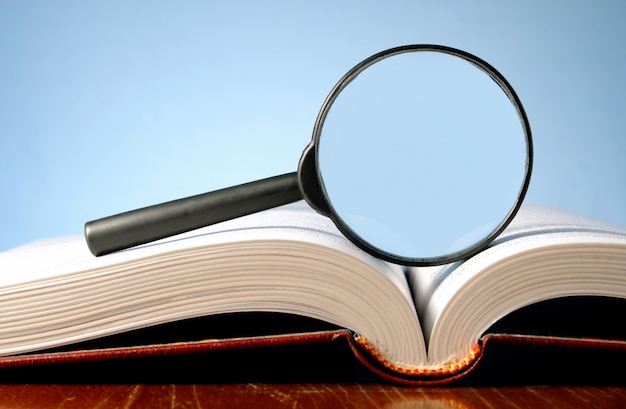 Book and a magnifying glass on a blue background