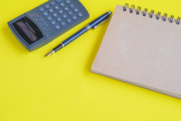 Book note and calculator on color background.