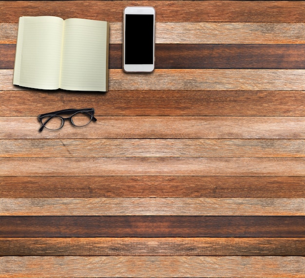 Книга смартфон и очки на фоне коричневого дерева