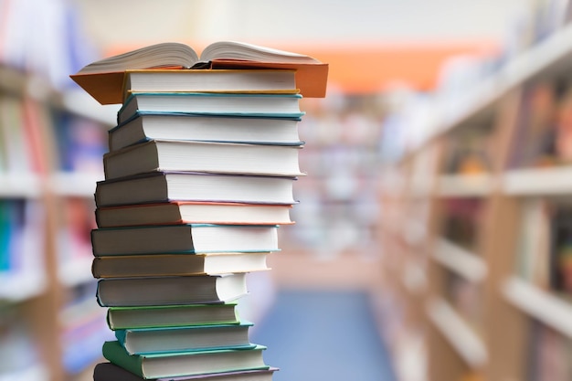 Book stacking. Open book, hardback books on library background