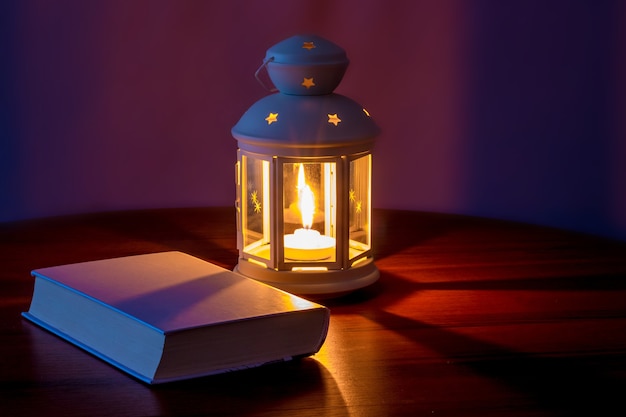 a book on the table at the light of a lantern with a candle in the evening