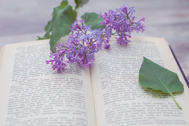 A book on a table with a lilac flowers on it