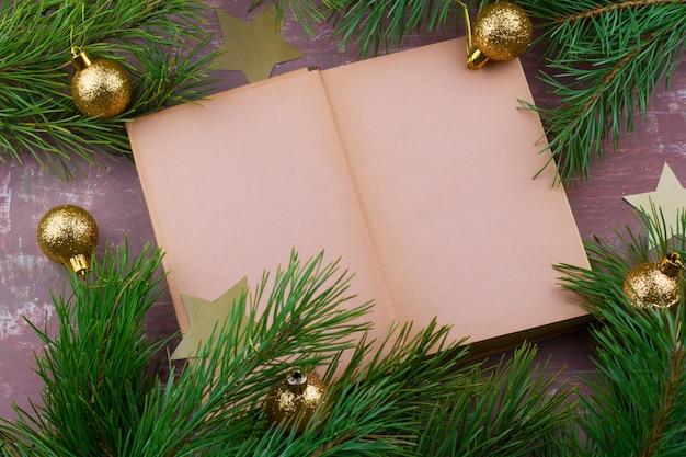   book with empty paper sheets and fir green branches with christmas golden balls 