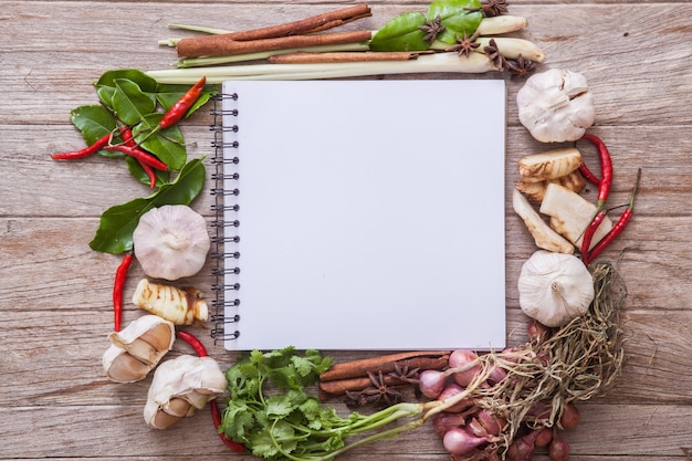 Book with herbs and spices on wooden