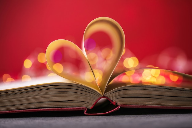 Photo book with love symbol on red background, heart shape from paper book.