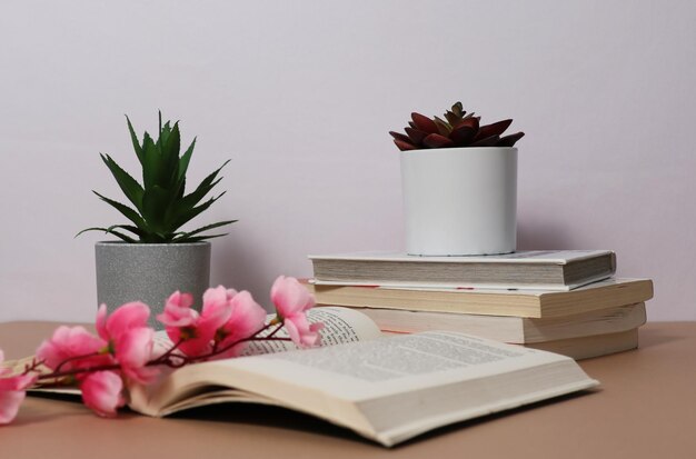 A book with a pink flower on it is open to a plant on a table.