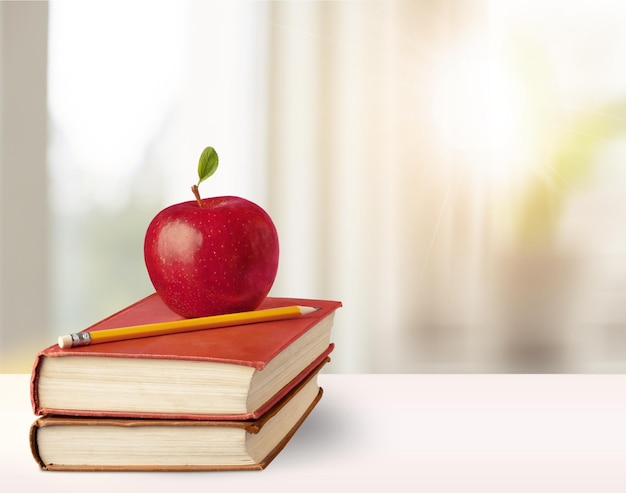 Books, apple and pencil on wooden table