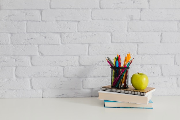 Books, apple and pencils on the table