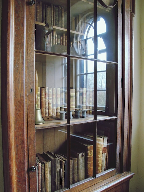 Photo books and bell on shelf in glass cabinet