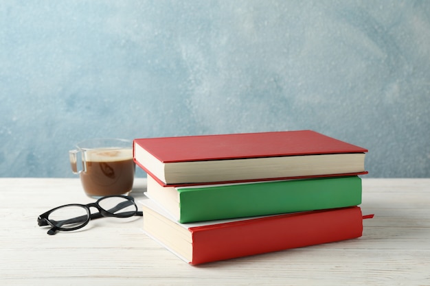 Books, cup of coffee and glasses on wooden table, space for text