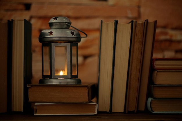 books and decorative lantern on table and brick wall background