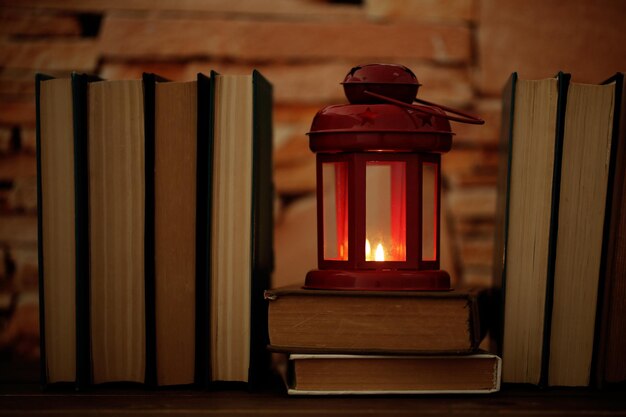books and decorative lantern on table and brick wall background