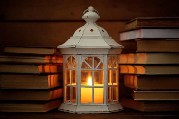 Books and decorative lantern on table and wooden planks background