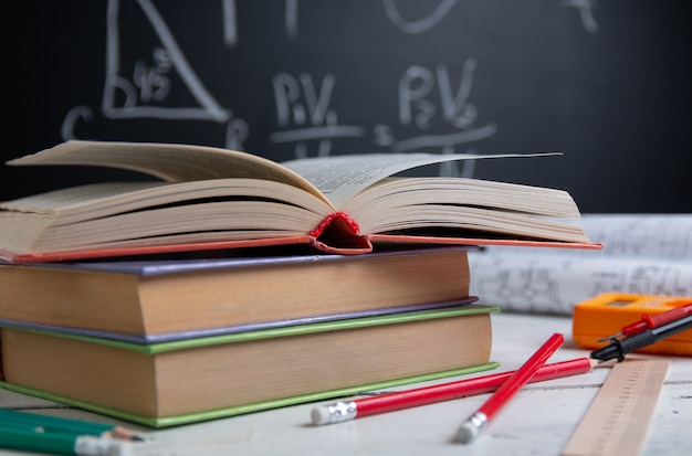 Books, digital multimeter, ruler and pencils on blackboard. Education concept.