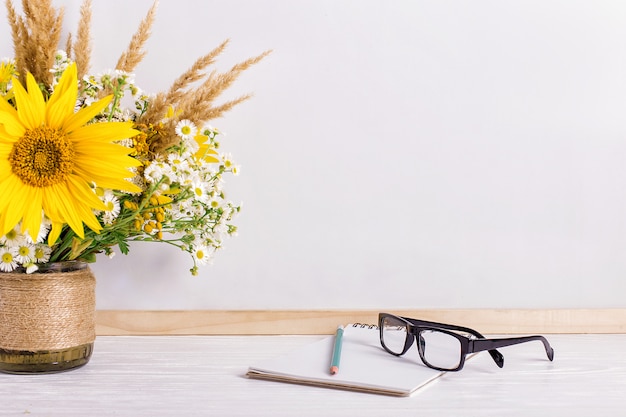 Books, glasses, markers and a bouquet of flowers in a vase on white 