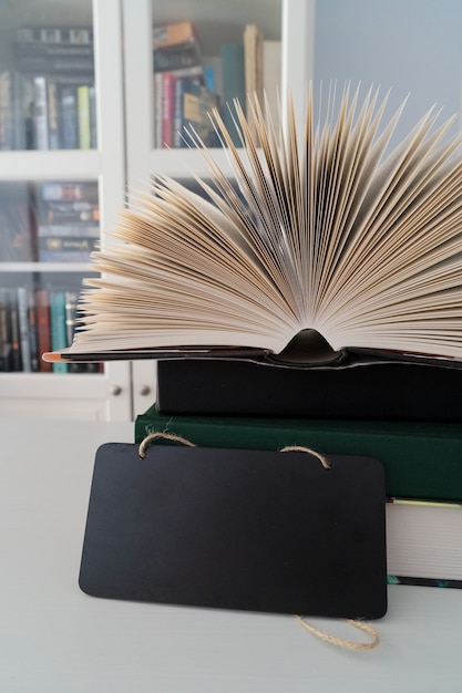 Фото Книги в библиотеке, открытые книжные страницы с книжными полками на заднем плане, место для копирования на черном сланце