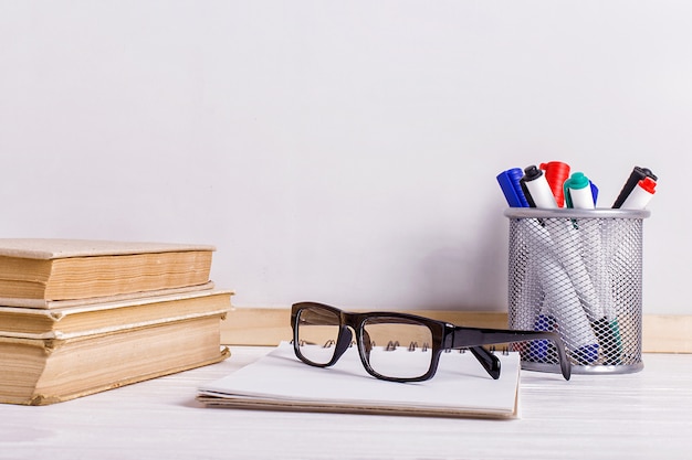 Books, markers, notebook, pencil and glasses on the table