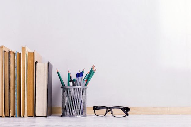 Books, markers, notebook, pencil and glasses on the table