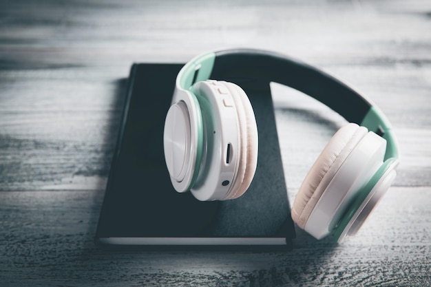 Books and modern headphones on light blue background top view