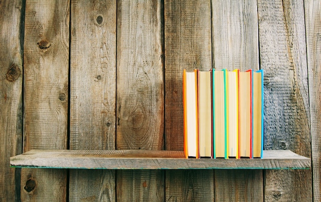 Фото Книги на деревянной полке на деревянном столе.